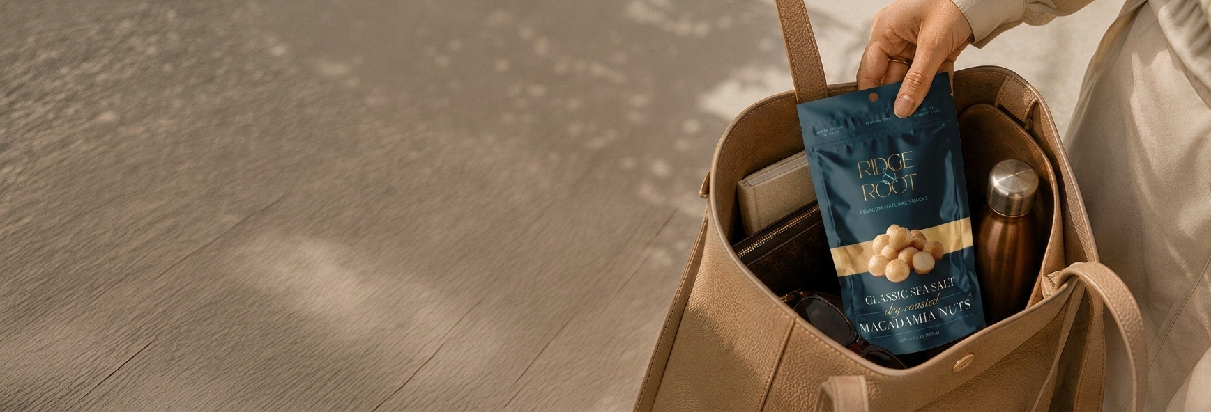 A hand holding a Classic Sea Salt Ridge & Root macadamia pouch over a canvas tote bag