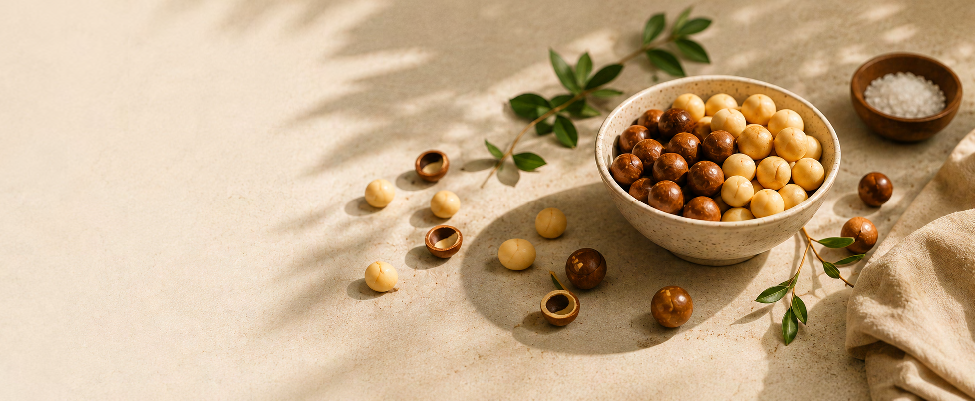 An assortment of roasted macadamia nuts and seasonings on a cream surface